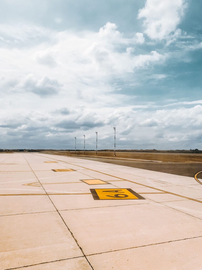 Expansive view of an empty airport runway marked with a number, under a partly cloudy sky.